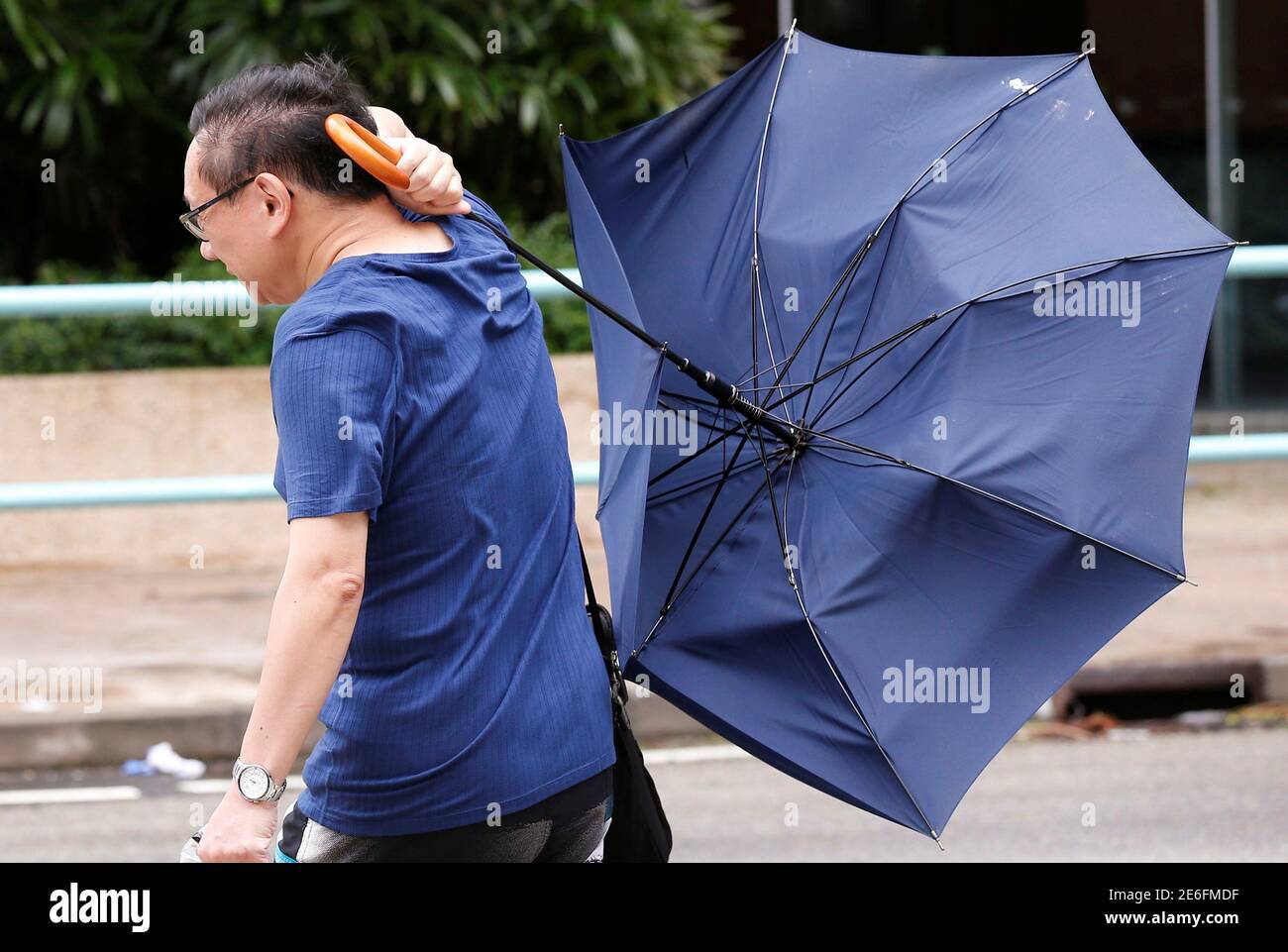 A man struggles with an umbrella while walking against strong wind as Typhoon Nida hits Hong Kong, China August 2, 2016.  REUTERS/Tyrone Siu Stock Photo