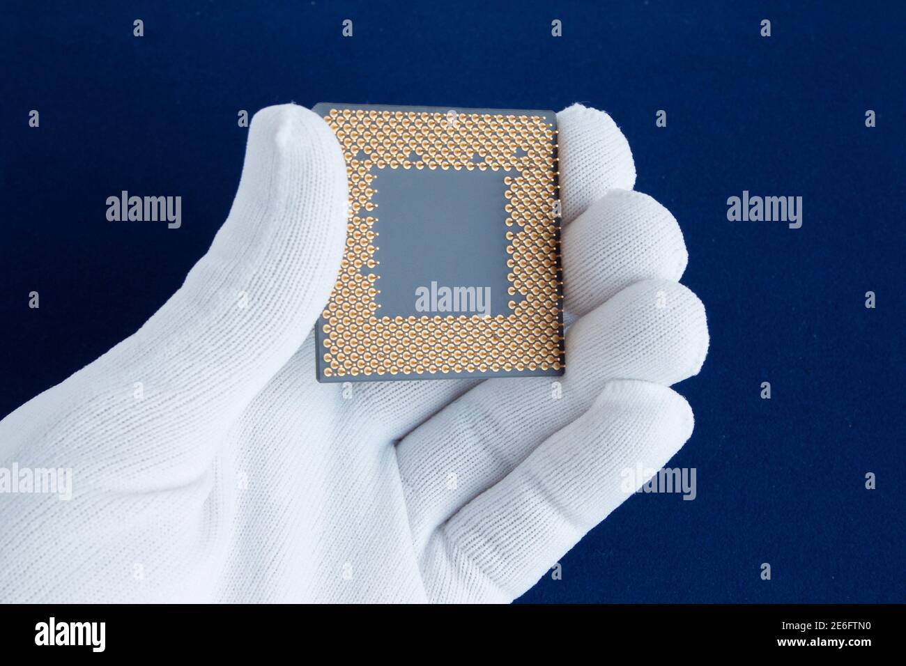 Hand in white glove holds the CPU. Closeup. Isolated on a white background. Stock Photo