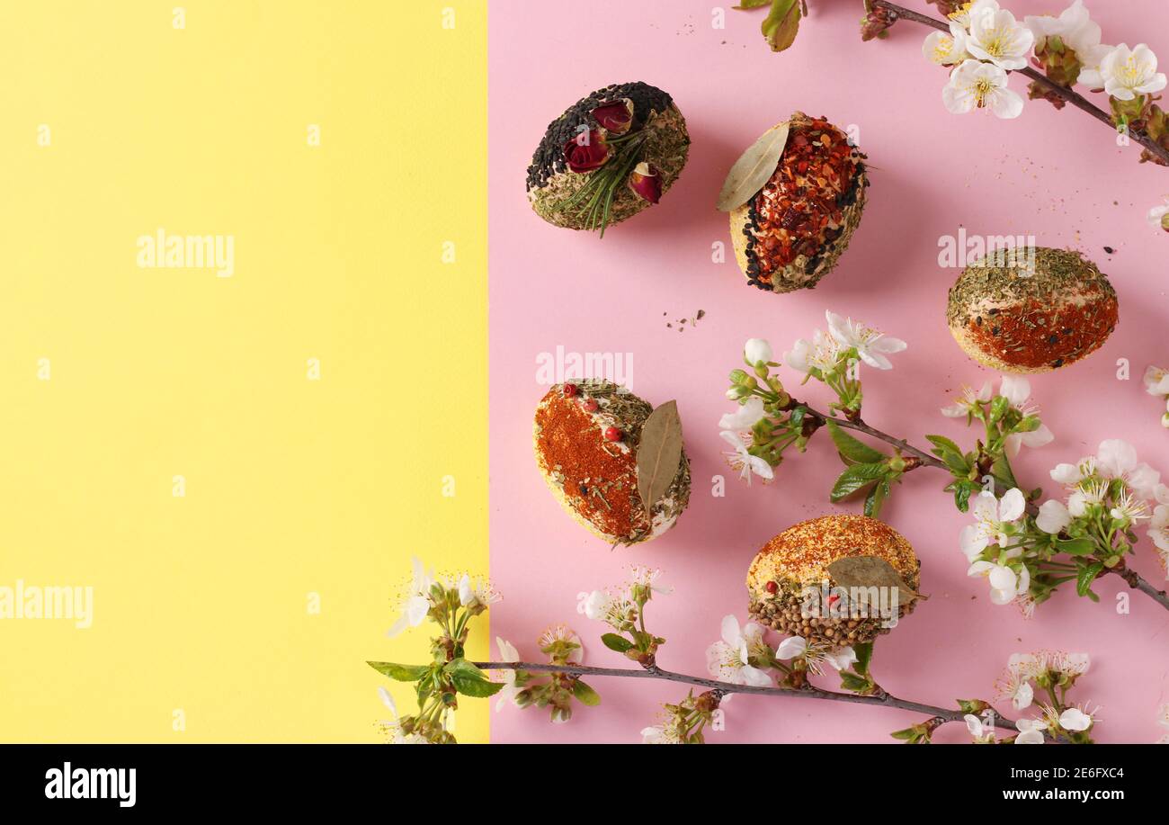 Easter concept with eggs decorated with different spices and cereals without dyes and preservatives on pink and yellow background. Space for text Stock Photo