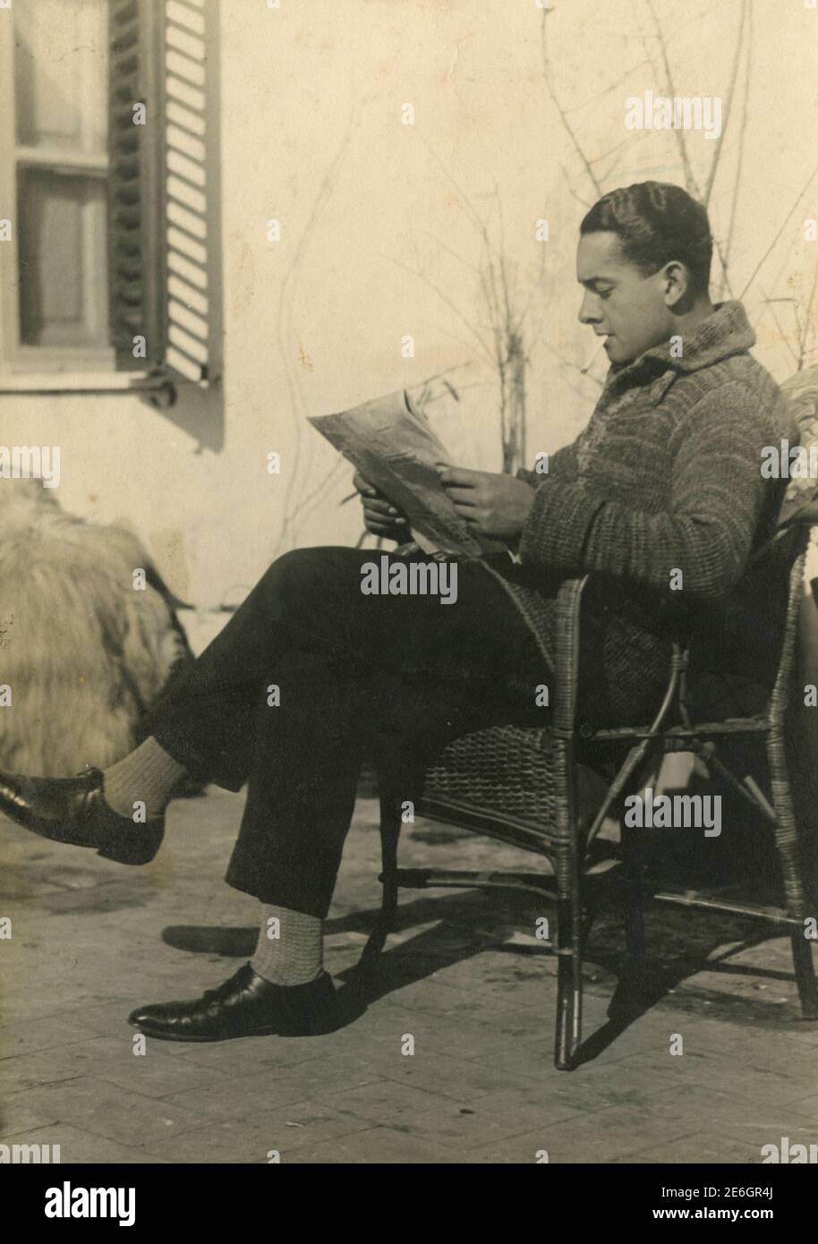 Man reading the newspaper on a chair outside, Italy 1931 Stock Photo
