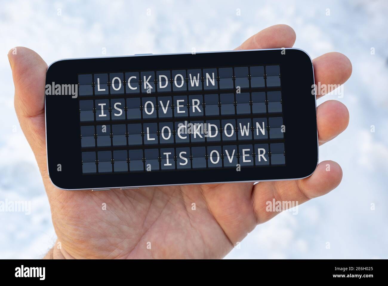 man holds a smartphone in his hand with the text message LOCKDOWN IS ...