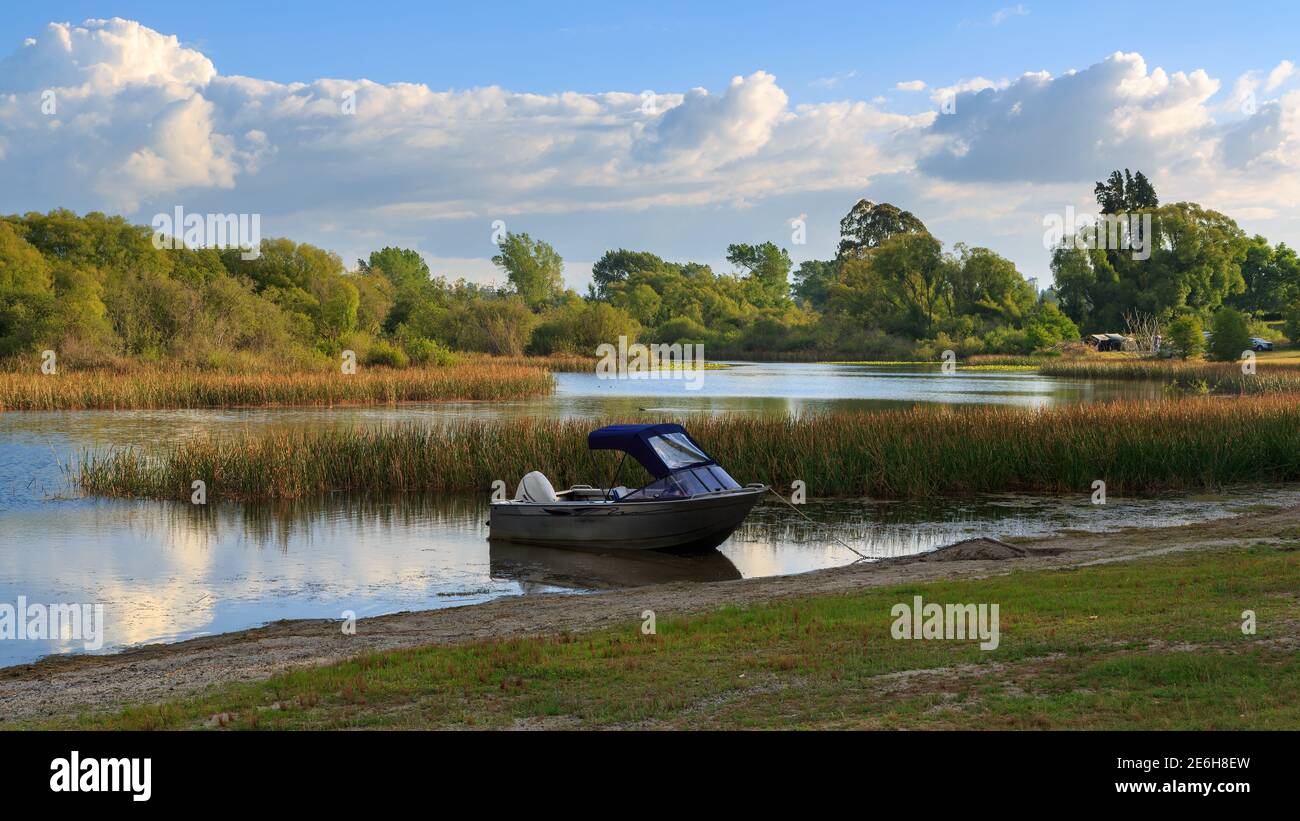 Small power boat resting on the shore of a quiet lake. Photographed at Lake Rerewhakaaitu in the Rotorua area, New Zealand Stock Photo