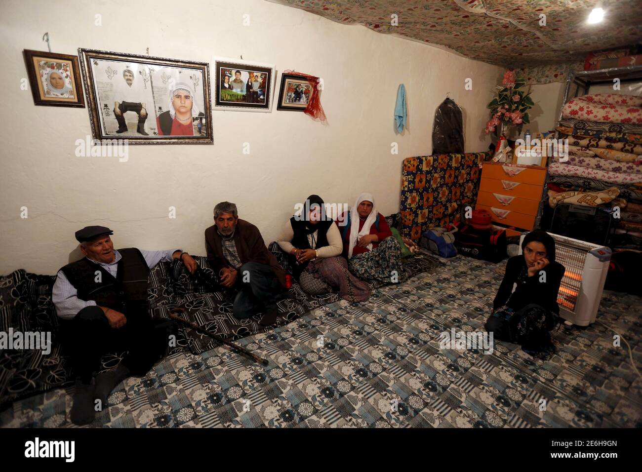 Sevgi Gezici (R), widow of Engin Gezici, sits next to her family members at their house in the southeastern town of Silvan in Diyarbakir province, Turkey, December 7, 2015. The shepherd's widow no longer asks God for peace. Like many Kurds in Turkey's southeast, Sevgi Gezici, 22, believed President Tayyip Erdogan would relent in a violent clampdown against Kurdish militants after his party won back its majority in an election in November. Three days after the vote, her husband, just back from seven months tending sheep, was shot dead in the street, caught in the crossfire as he ventured out of Stock Photo