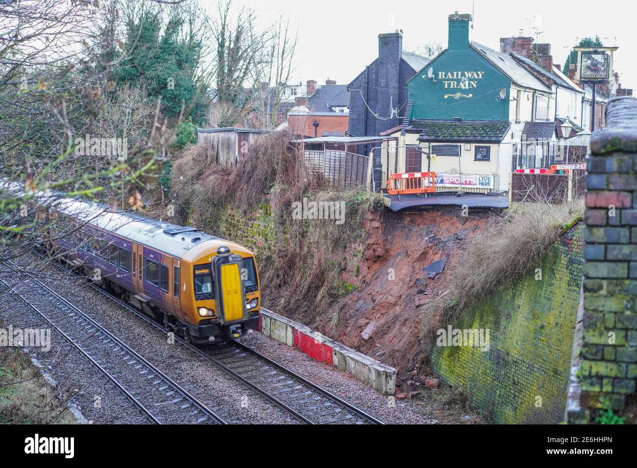 Kidderminster, UK. 29th January, 2021. Services are back on track today after a landslip at the Railway Train Inn in Kidderminster yesterday. All rail services were suspended after tons of earth moved towards the rail track from the side of the public house. A temporary barrier has now been put into place and train services through Kidderminster have quickly resumed but will be passing the area at crawling speeds just in case of any further landslip. Credit: Lee Hudson/Alamy Live News Stock Photo