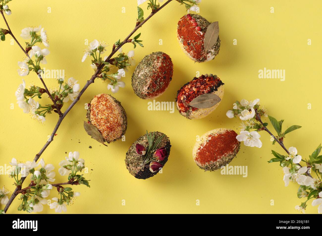 Easter concept with eggs decorated with different spices and cereals without dyes and preservatives on yellow background. View from above Stock Photo