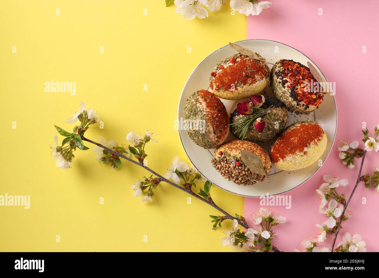 Easter concept with eggs decorated with different spices and cereals without dyes and preservatives on pink and yellow background. View from above Stock Photo