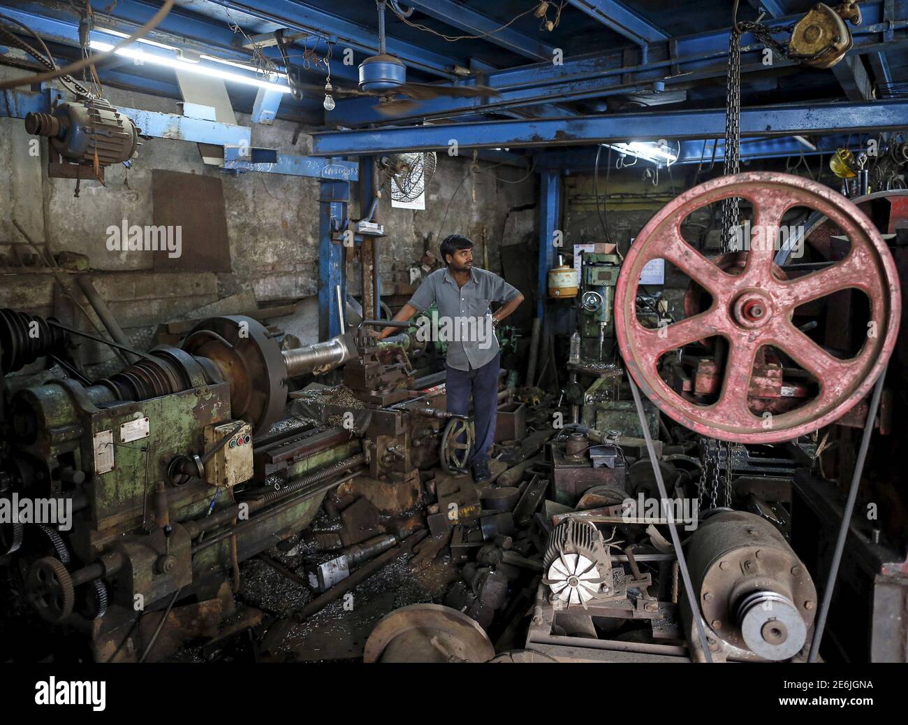 A worker looks on as he operates a machine making gear parts for cranes, inside a workshop in an industrial area in Mumbai, India, January 12, 2016.  India's annual industrial output contracted 3.2 percent in November, government data showed on Tuesday. REUTERS/Danish Siddiqui Stock Photo