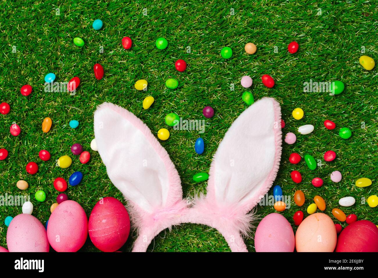 Colored eggs and vibrant candies on grass. Easter composition Stock Photo