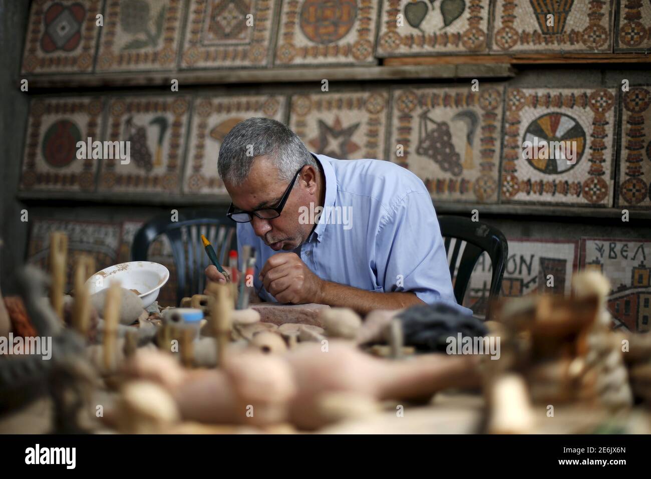 Archeology Nafez Abed cleans sculptures at his workroom, at Shati refugee camp in Gaza City, November 8, 2015. Nafez Abed's cramped workroom is filled with sculptures and intricate mosaics decorated with patterns from the Byzantine, Greek and Roman periods. It is an emporium of Middle Eastern antiquity tucked away in Gaza. And none of it is real. Picture taken November 8, 2015. To match story PALESTINIANS-ARCHAEOLOGY REUTERS/Suhaib Salem Stock Photo