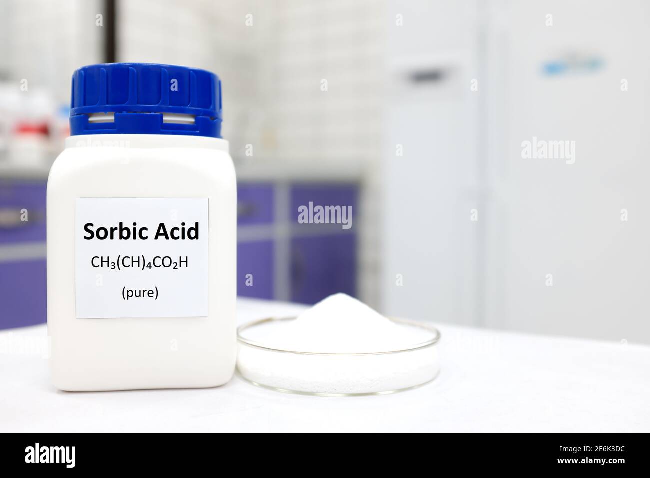 Selective focus of bottle of pure sorbic acid food additive beside a petri dish with white solid powder substance. White laboratory background. Stock Photo