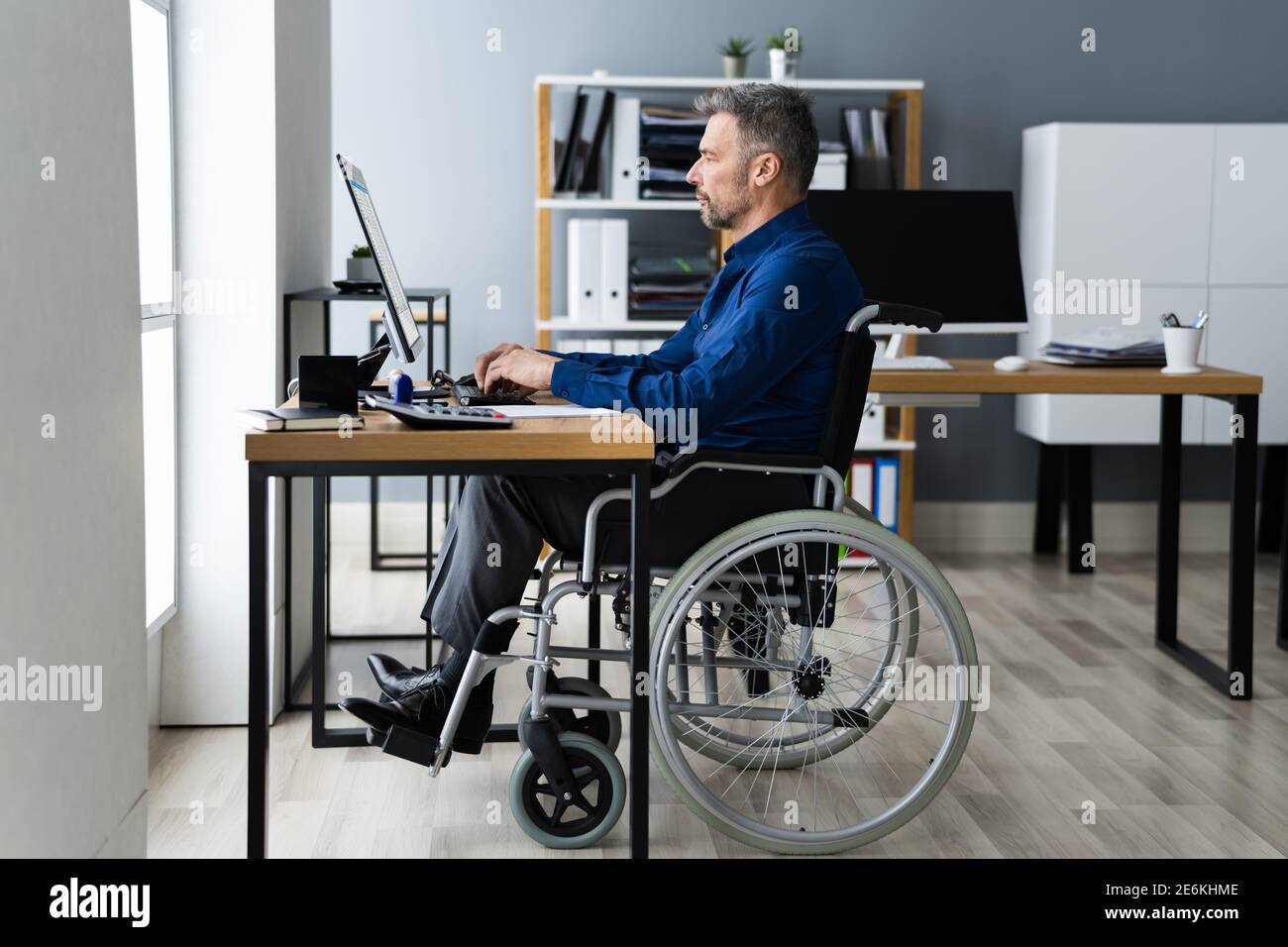 Disabled Handicapped Man In Wheelchair Working Using Computer