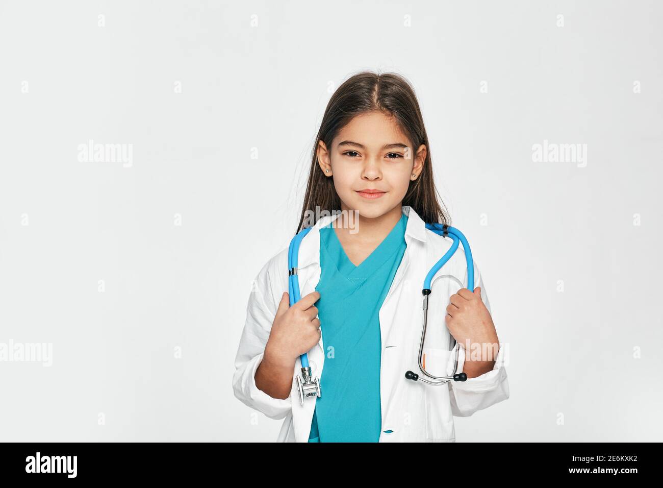 Portrait of mixed race little girl dressed as a doctor with stethoscope, she posing and looking at camera. Light grey background Stock Photo