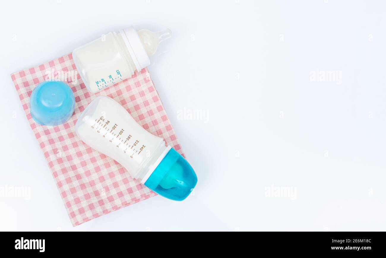 Feeding bottles of baby formula with powder and pacifier on white