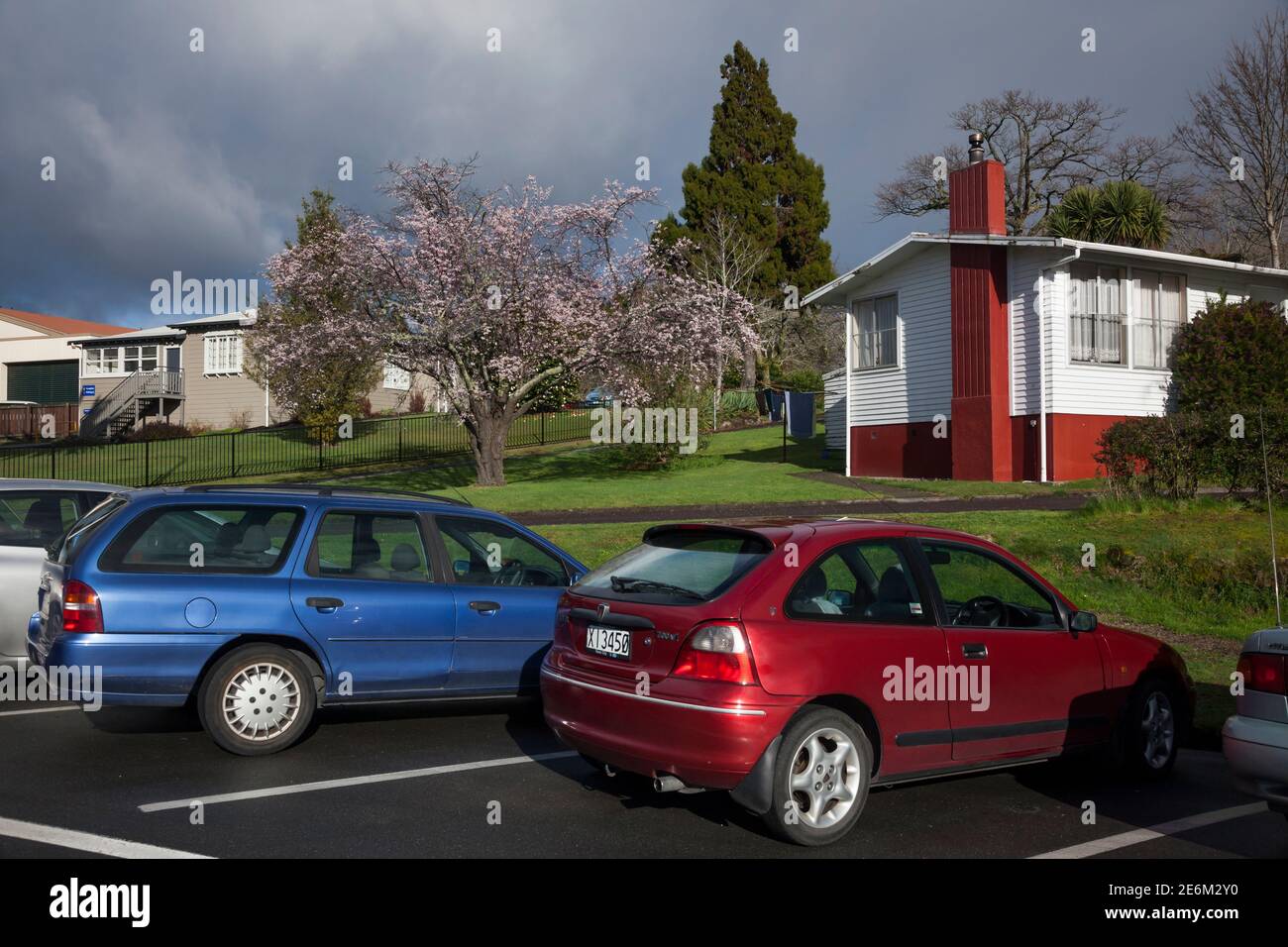 Horizontal shot of some cars parked in Rainguru St in front of a colorful detached house garden, Rotorua, North Island, New Zealand Stock Photo
