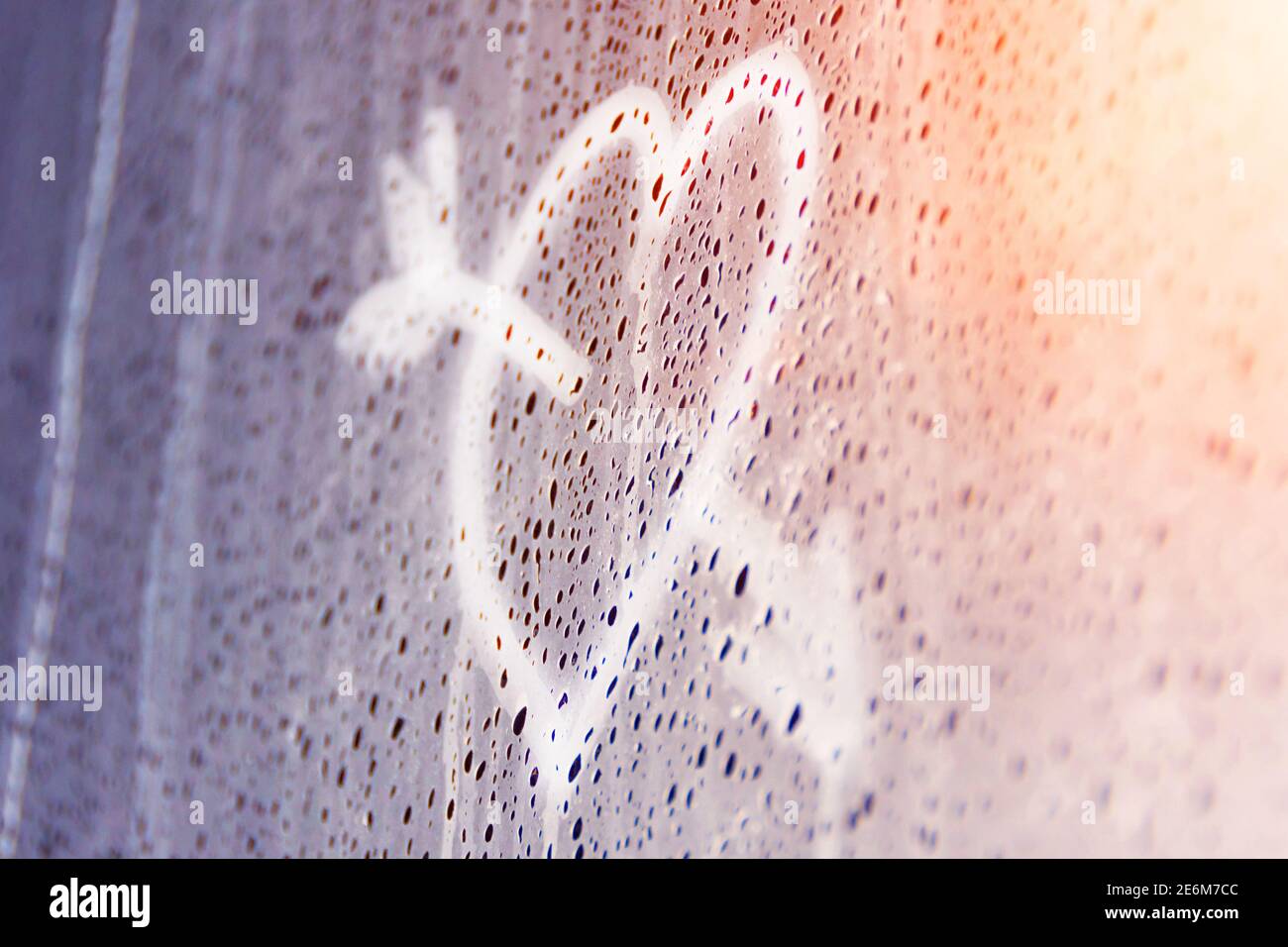 Heart pierced by an arrow painted on misted glass, a symbol of feelings of love and relationships. The first love Stock Photo