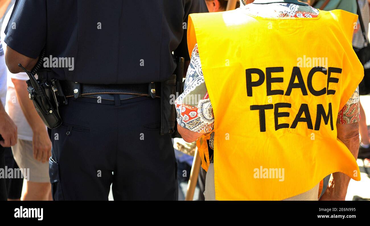 A peace team member (R) listens as a Cleveland police officer talks with demonstrators before the start of a protest march down Euclid Avenue against the Republican National Convention in Cleveland, Ohio, July 17, 2016. REUTERS/Steve Nesius. Stock Photo