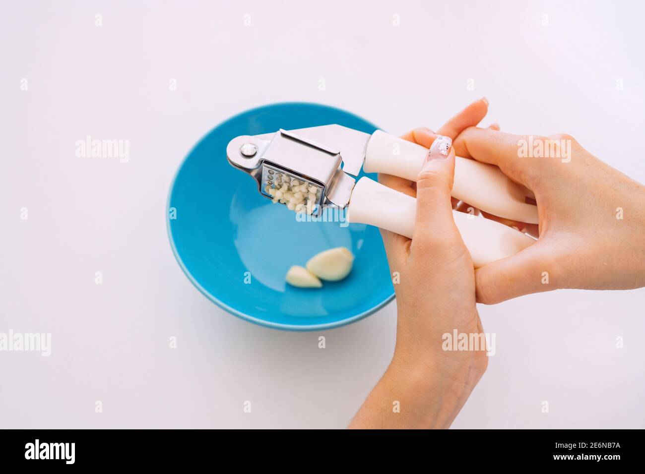 Garlic crushed using a garlic press. Female hands using a garlic press