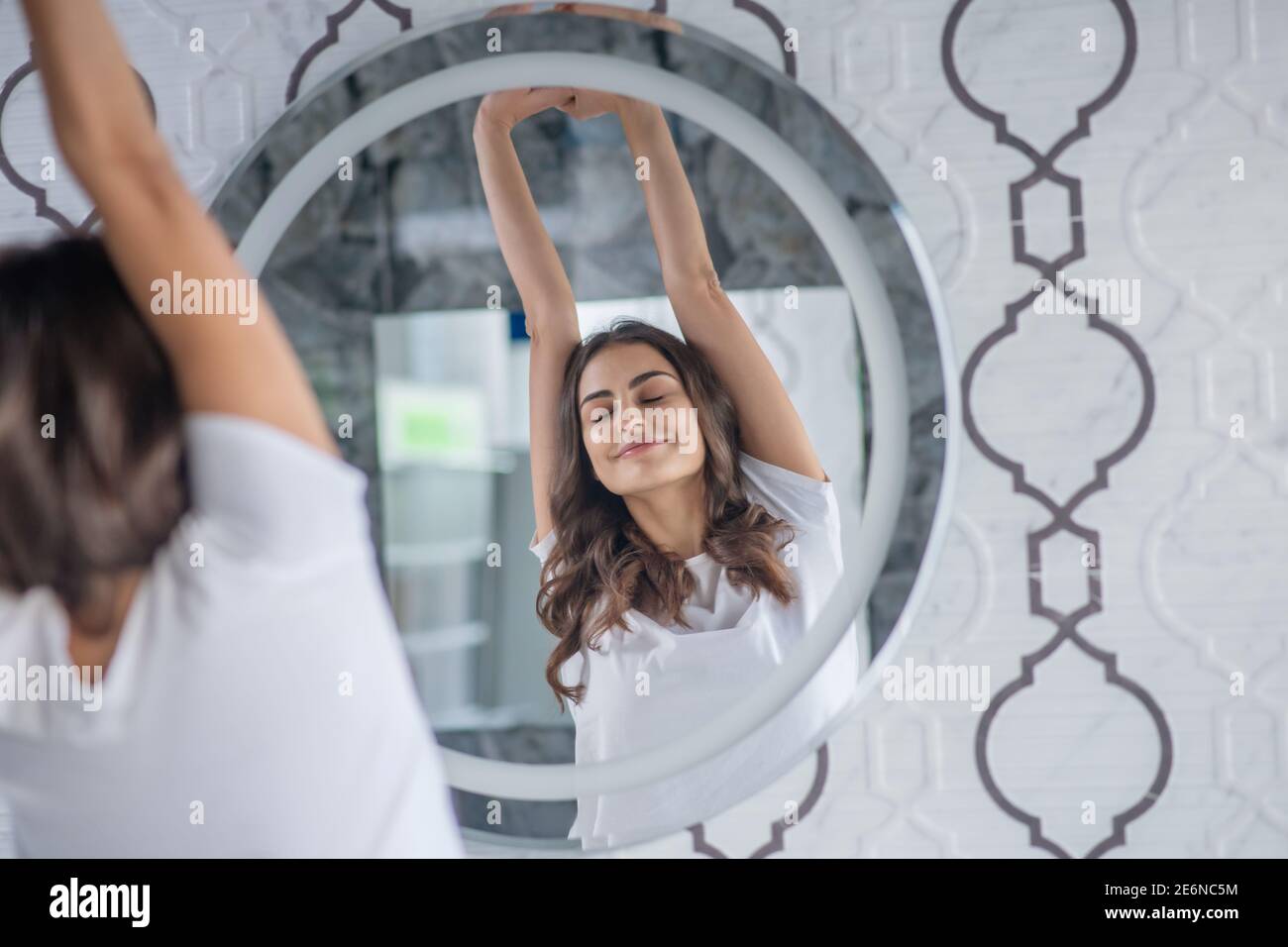 Woman stretching her back near the mirror Stock Photo