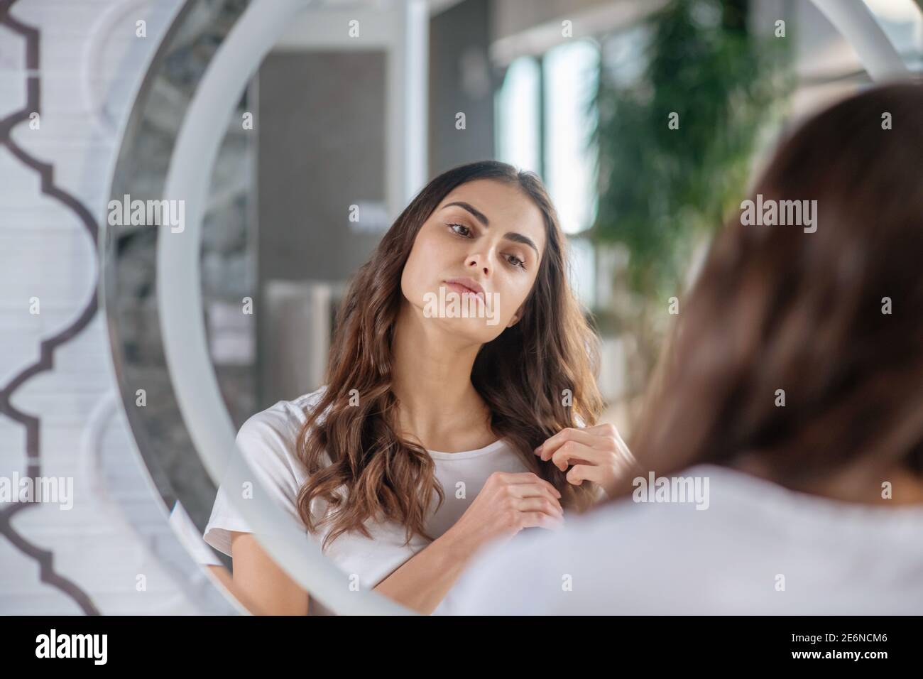 Woman checking her hair tips near the mirror Stock Photo