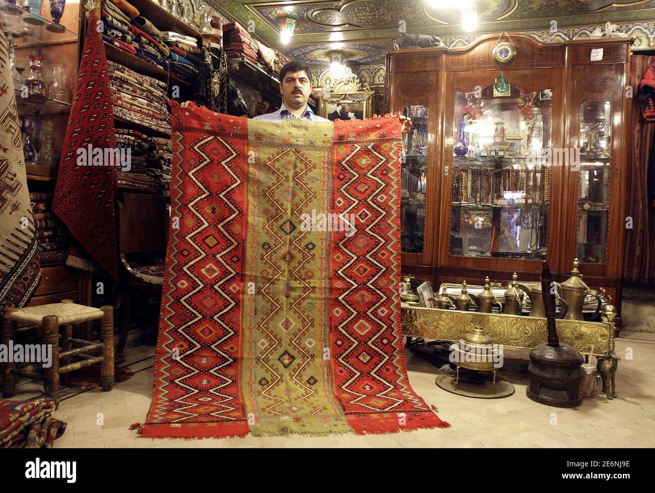 A man displays an antique rug, or kilim, from the Syrian Ifrin region a shop at the main market of the Syrian city of Aleppo June 23, 2010. Subtlety is the