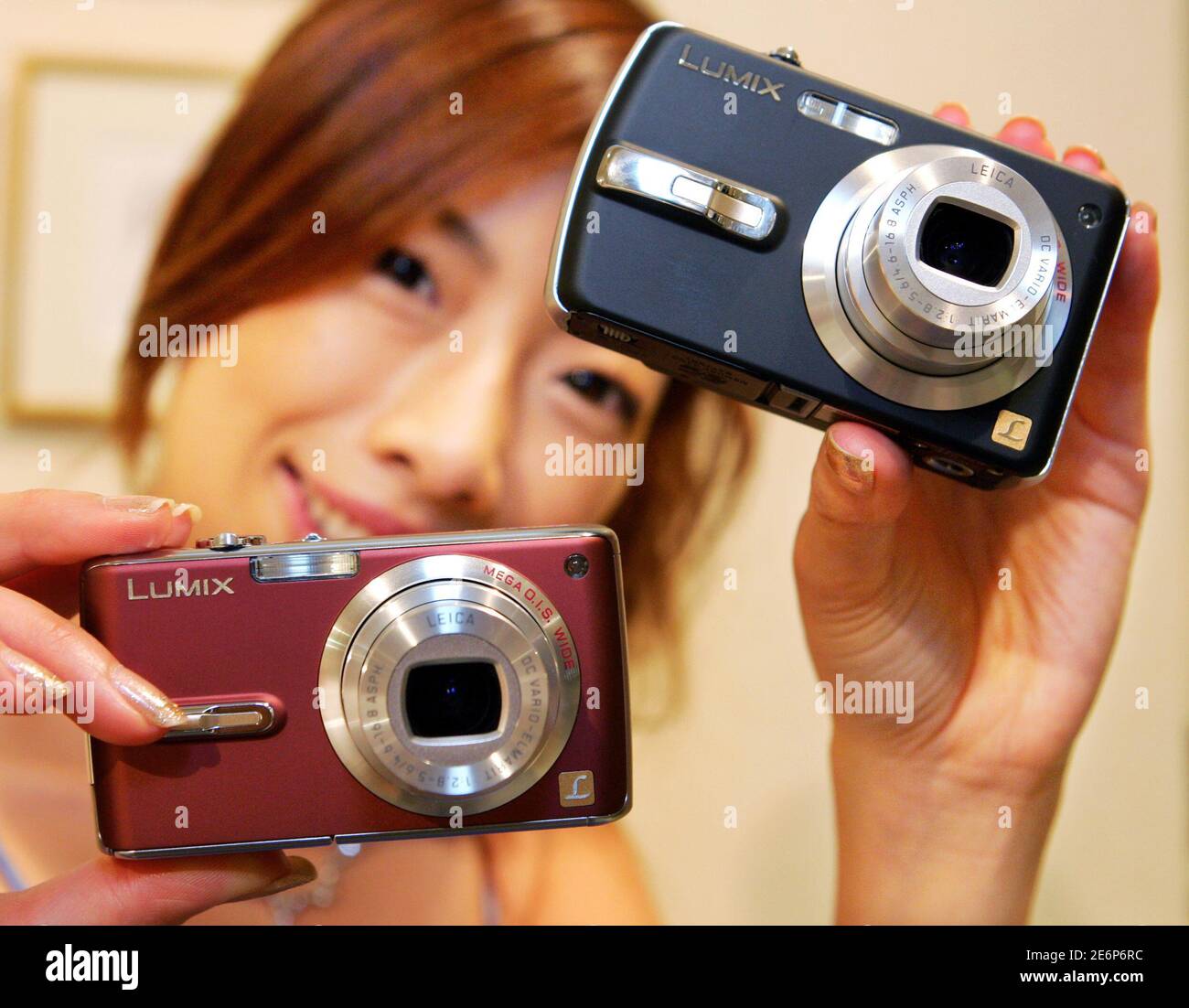 A model presents Panasonic's new "LUMIX" digital still cameras DMC-FX07  (bottom) and DMC-FX50 at an unveiling in Tokyo July 25, 2006. Manufactured  by Matsushita Electric Industrial Co., the 7.2-megapixel cameras, equipped  with