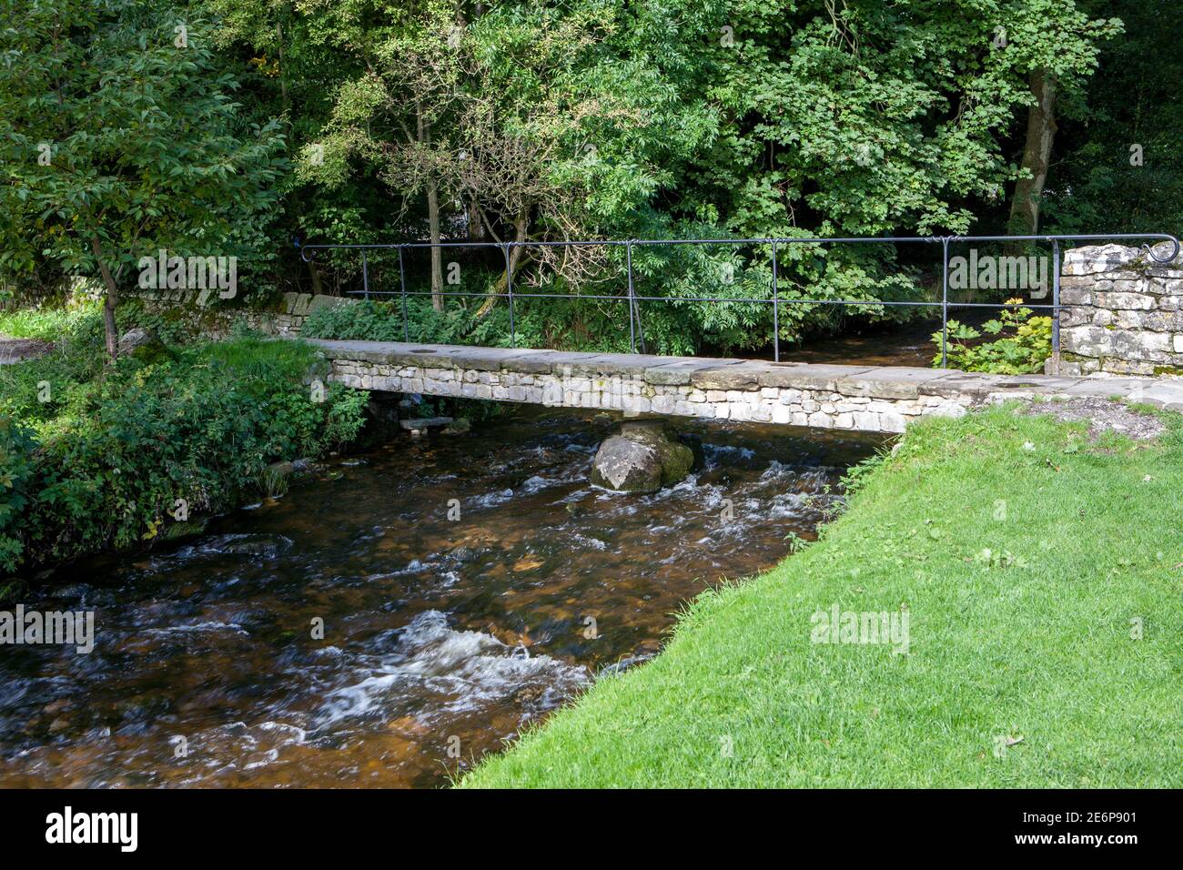 Summer view of a clapper style footbridge over Malham Beck in Malham