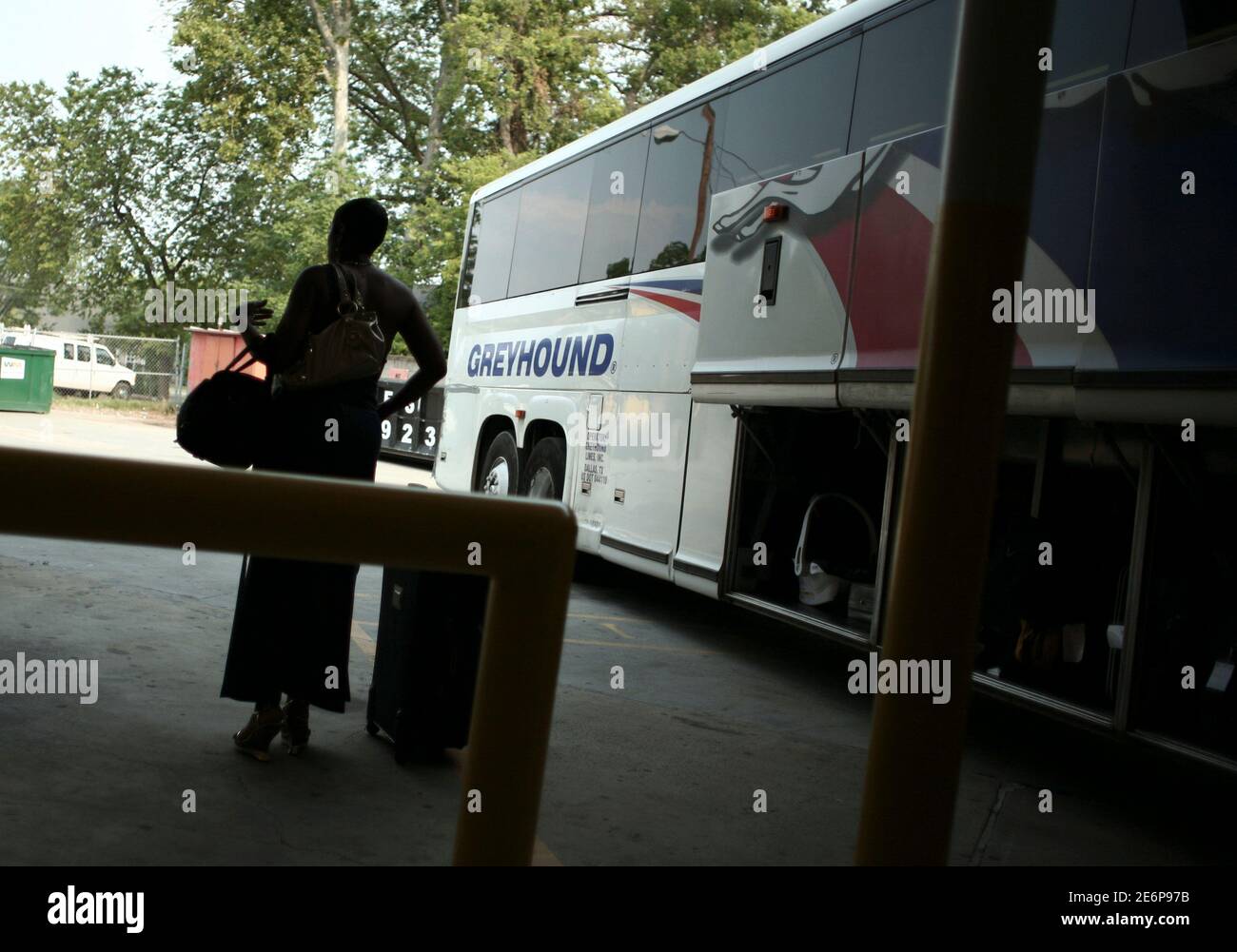 A woman stands next to a Greyhound bus at a bus station in Columbus,  Georgia, May 11, 2007. Greyhound buses are largely perceived as an  affordable if time-consuming, travel alternative. The company