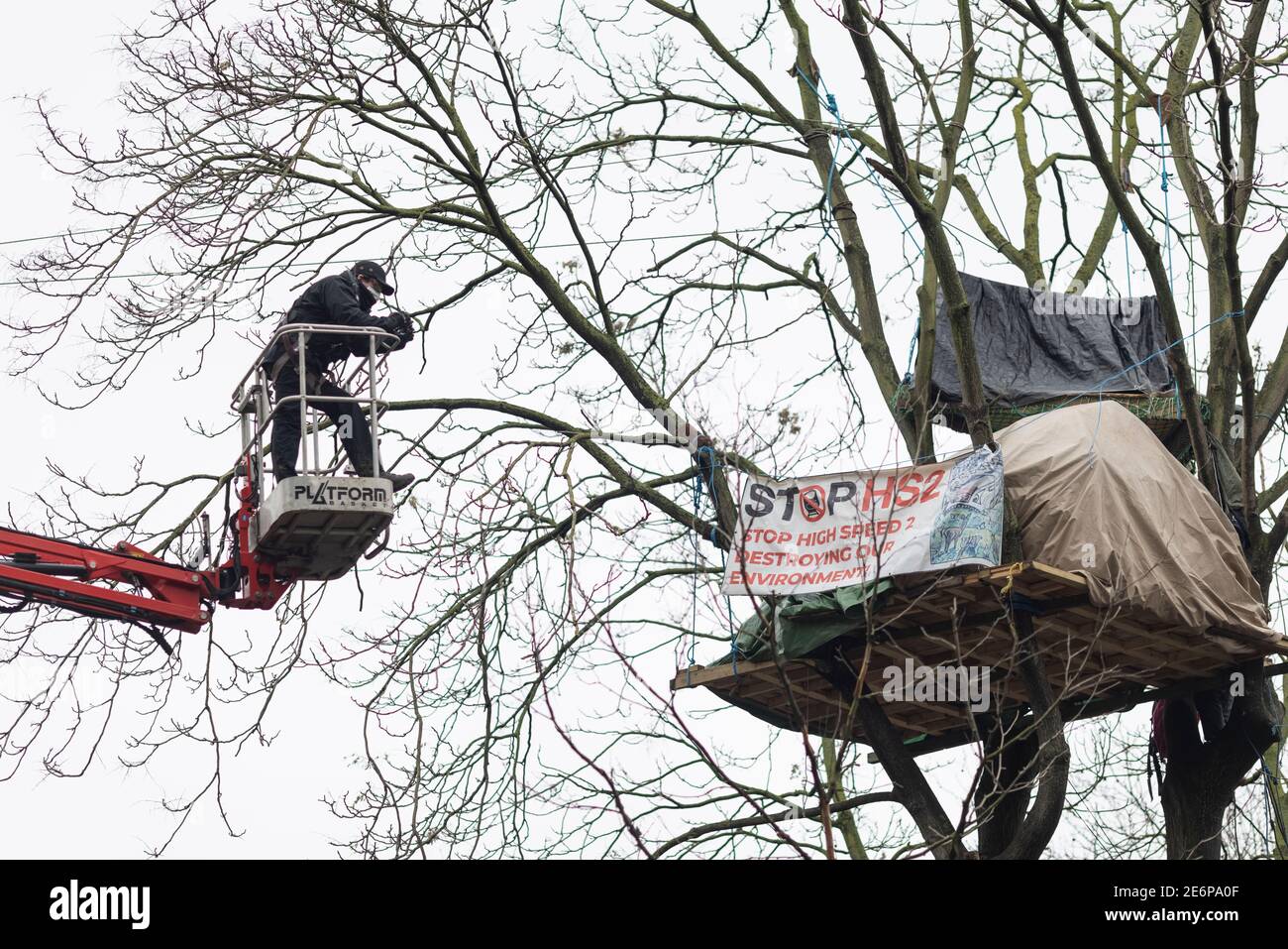 Eviction of Stop HS2 protesters from campsite at Euston Square Gardens, London, 27 January 2021. A member of the eviction team observes protester's Stock Photo