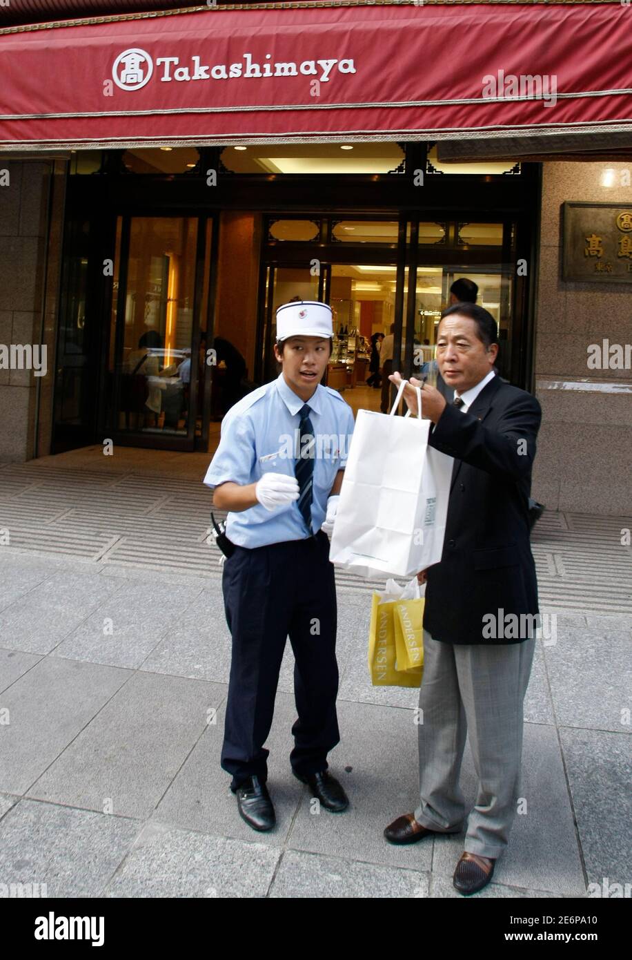 An employee of Takashimaya department store (L) attends to a customer in Tokyo September 3, 2007. Japanese department store retailer Takashimaya Co Ltd is unlikely to engage in mergers and acquisitions in the current market climate, company president Koji Suzuki told Reuters in an interview on Monday.    REUTERS/Kim Kyung-Hoon (JAPAN) Stock Photo