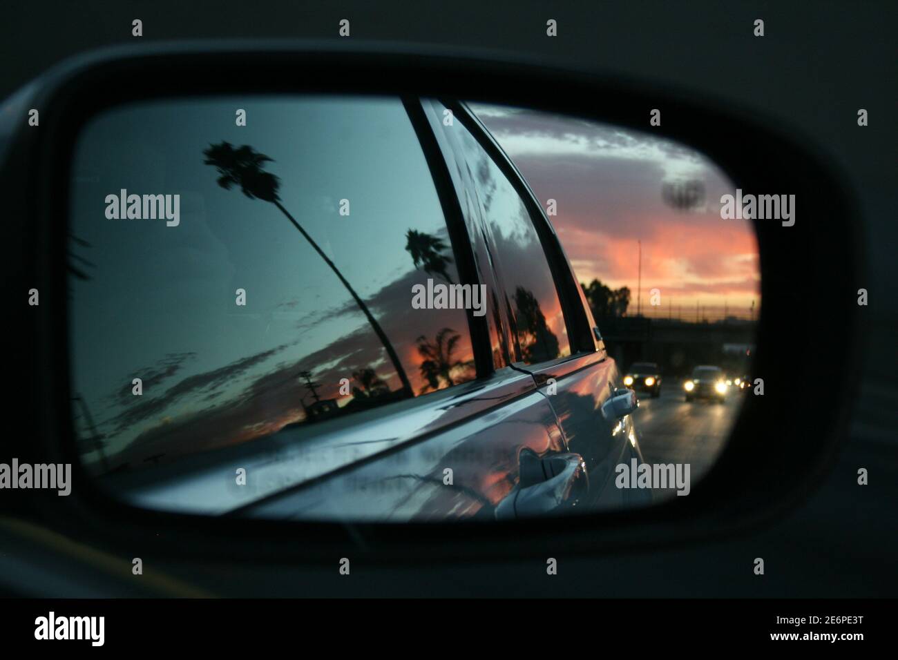 Sunset in Los Angeles seen from the side mirror of a car driving along