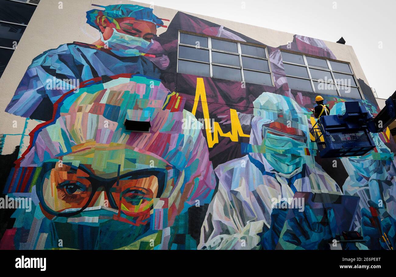 A worker makes final touches on the mural as a tribute to the frontliners amid the Covid-19 pandemic outside a hospital.Malaysia has recorded 5,725 new Covid-19 infections cases with sixteen fatalities in the past 24 hours. For the first time the number of infections has surpassed the 5,000 mark, which has brought the nation’s total number of infected individuals to 203,933. Stock Photo