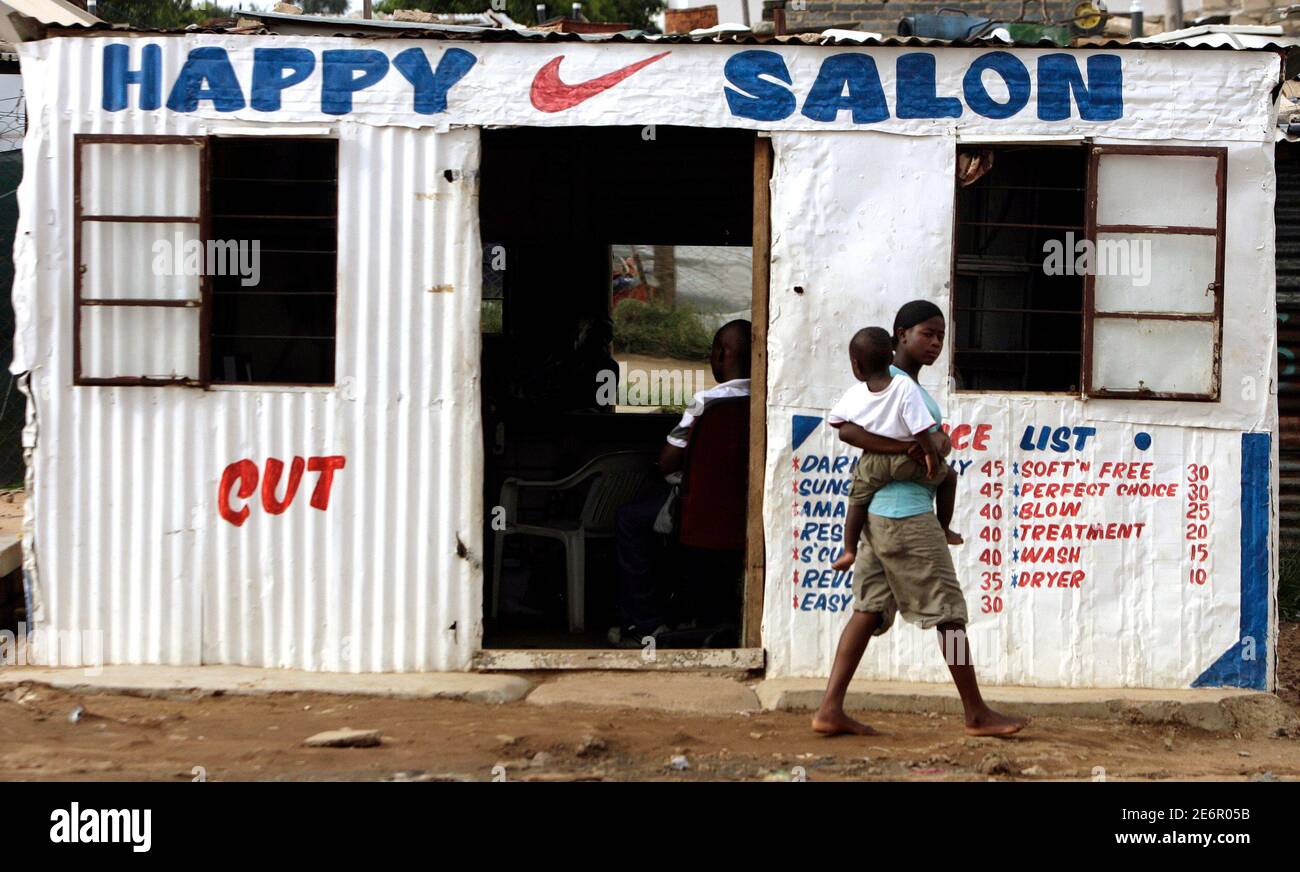 A woman and a child walk past a makeshift hair salon in a township outside  Johannesburg, January 25, 2009. The Congress of the People (COPE), South  Africa's new party, has shaken up