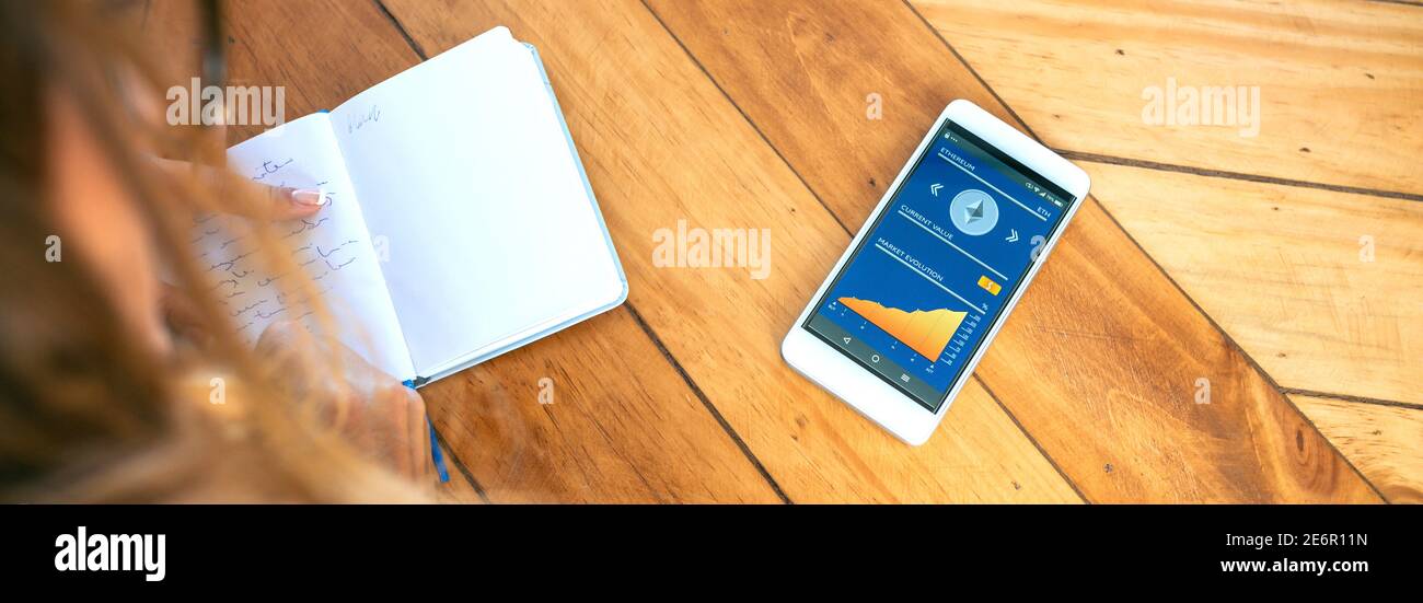 Businesswoman taking notes in agenda and mobile ethereum information Stock Photo