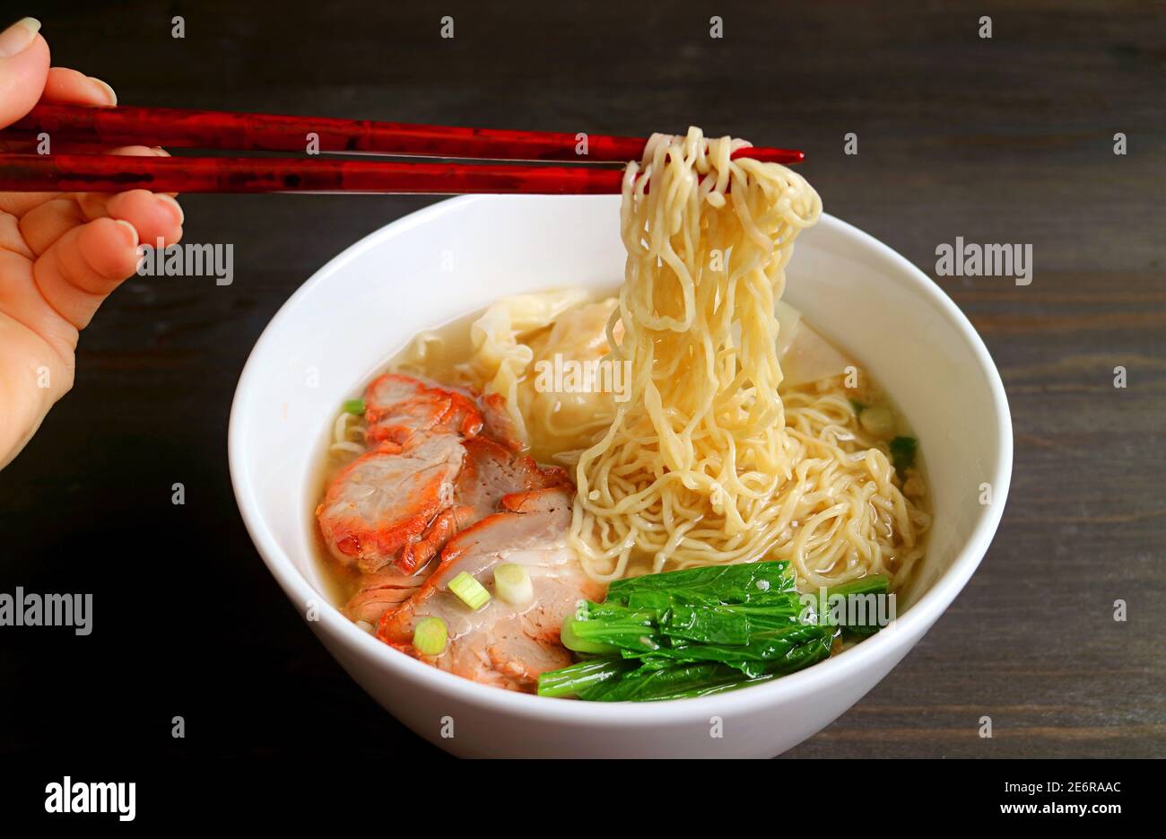Woman's Hand Grabbing Delectable Chinese Egg Noodle with Chopsticks Stock Photo