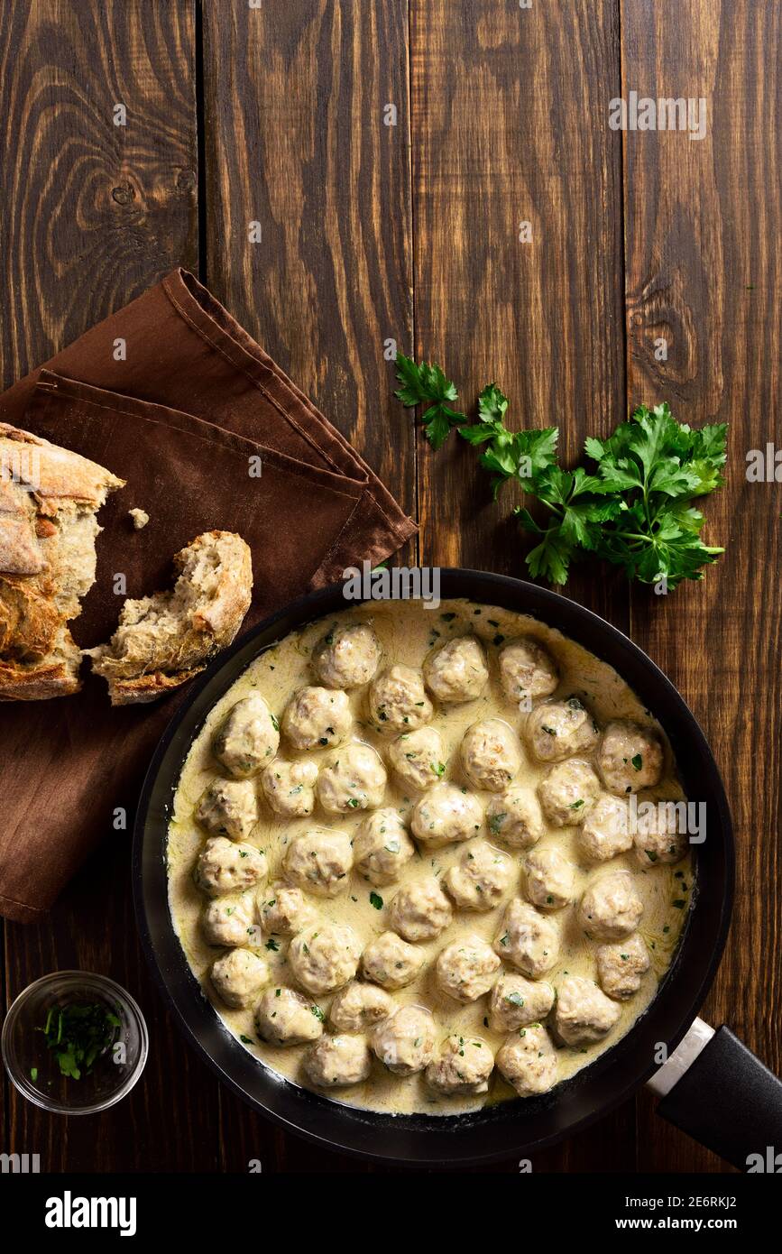 Delicious homemade swedish meatballs with creamy white sauce in frying pan over wooden background with free space. Top view, lat lay, close up Stock Photo