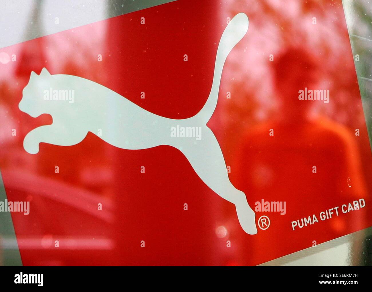 A man is reflected in a window with a Puma sign, at the factory outlet  store in Herzogenaurach near Nuremberg April 10, 2007. French retailer PPR  on Tuesday made a 5.3 billion