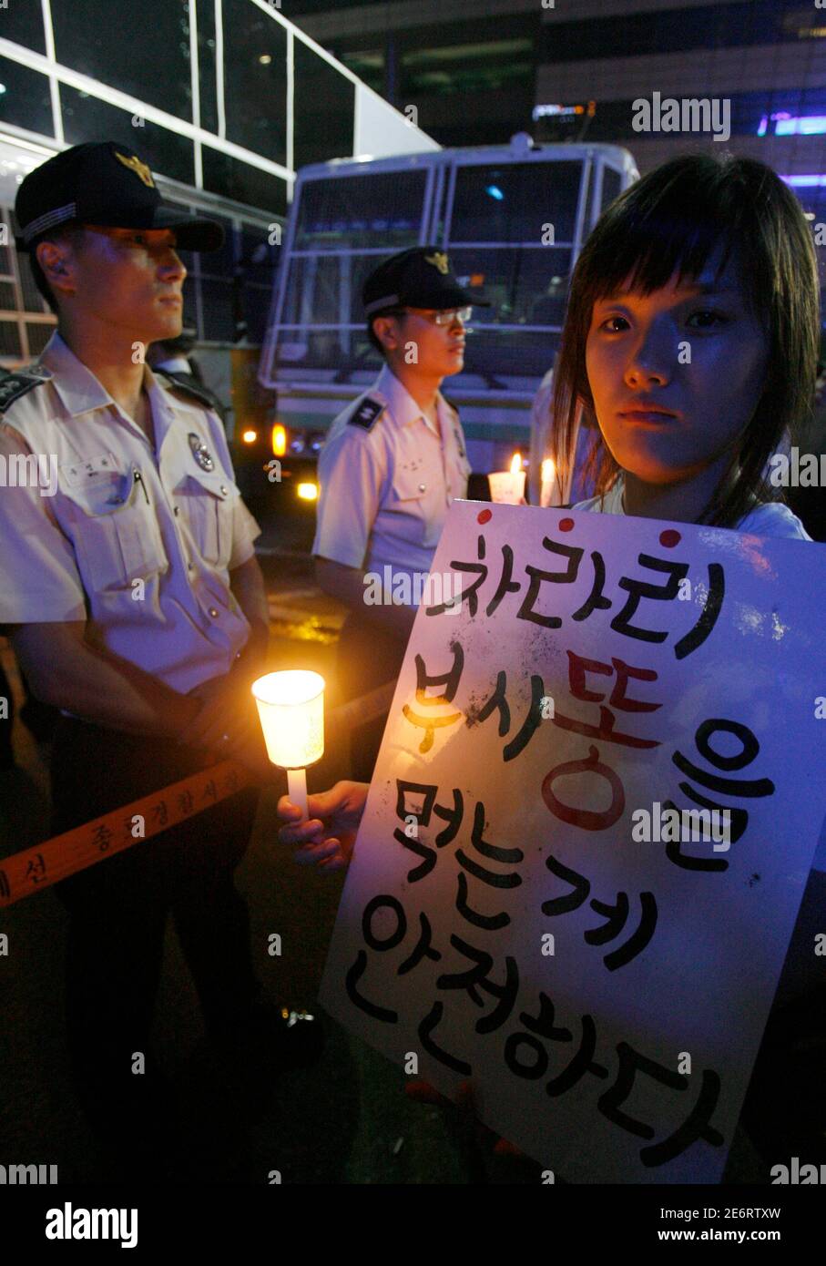 Policemen block a high school student demonstrating on the road leading to the U.S. embassy and the presidential Blue House during a candle-light rally to demand full-scale renegotiation of a beef deal with the U.S. and the resignation of President Lee Myung-bak in central Seoul June 13, 2008. Thousands of people participated in the rally after widespread South Korean concern over mad-cow disease in U.S. beef quickly became the lightning rod for a wide range of grievances against Lee's government. The Korean characters read,'It is safer that we rather eat excrement of (George W.) Bush (of U.S. Stock Photo