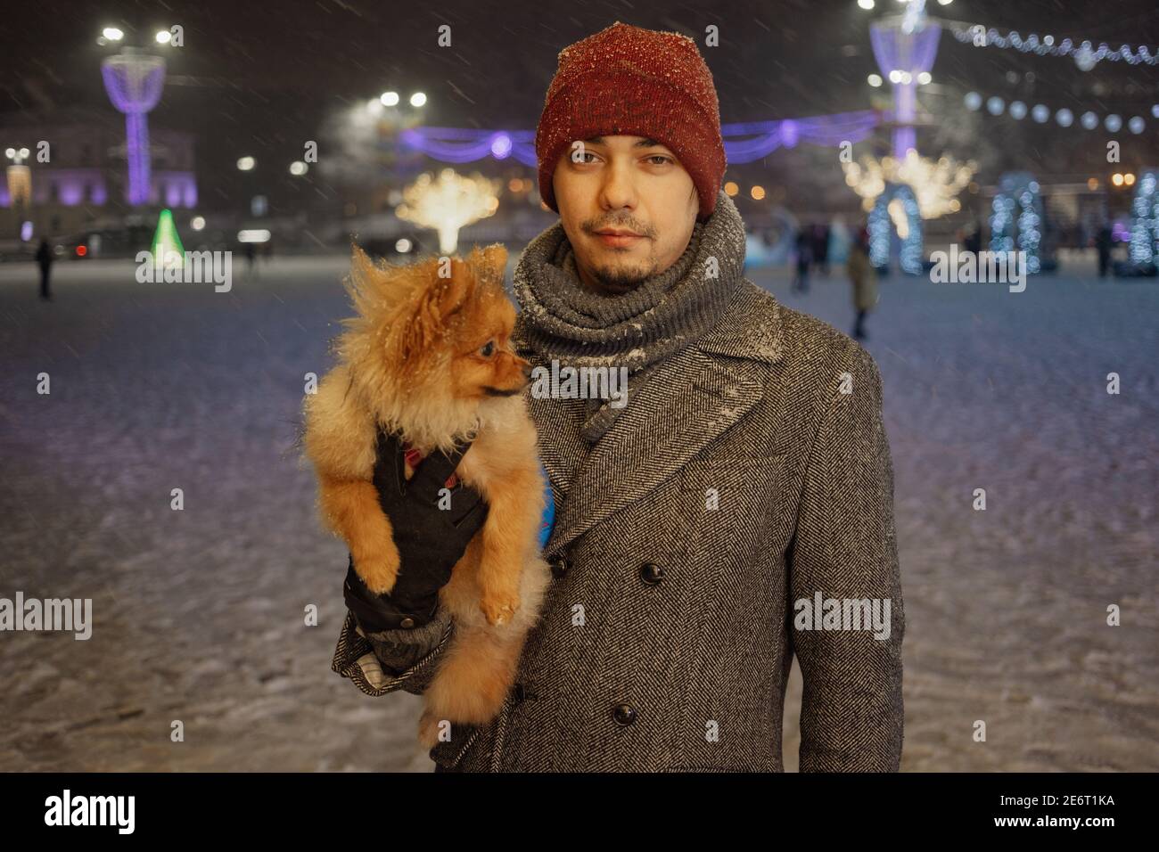 Image of young adorable man with his dog, pomerian, outdoor, under the snow. Winter time Stock Photo