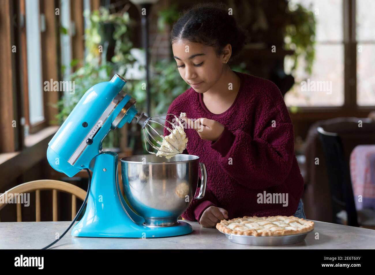 Woman whipping cream using electric hand mixer on the gray rustic wooden  table Stock Photo