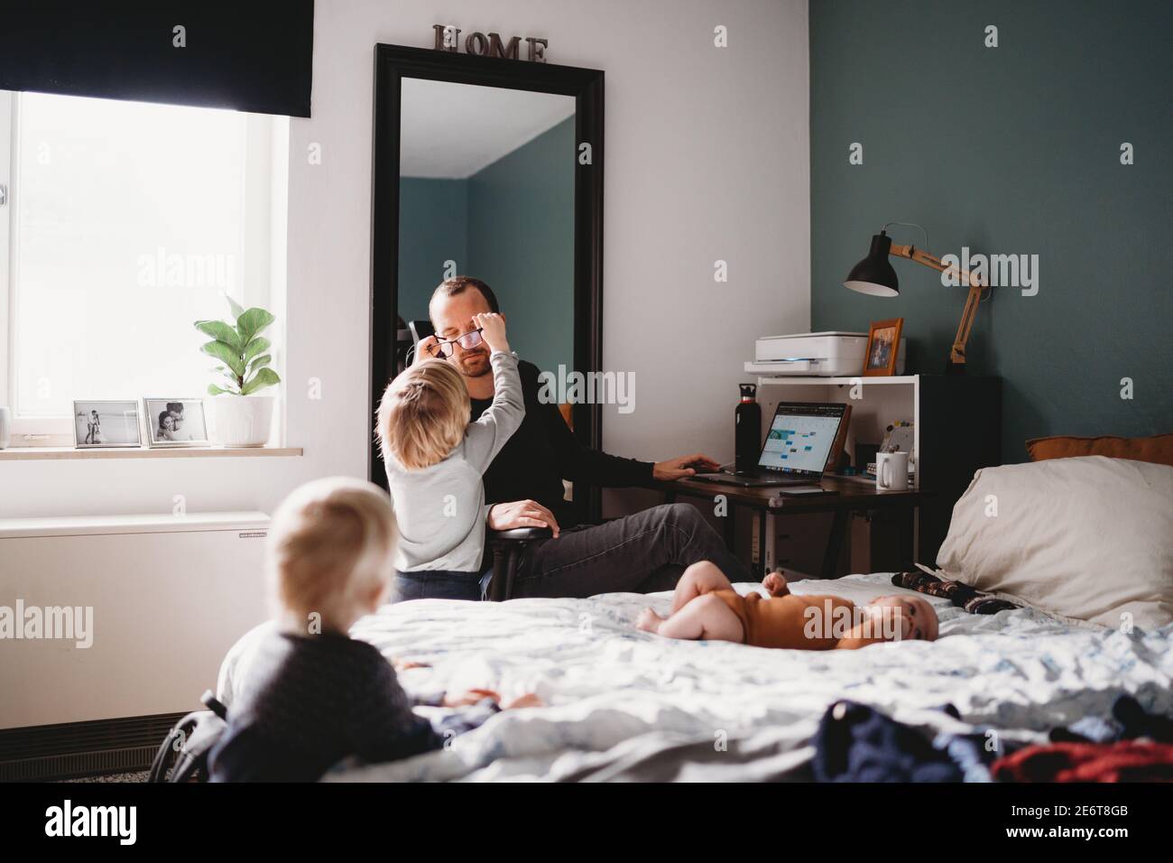 Parent sitting at home trying to work while young kids are around Stock Photo