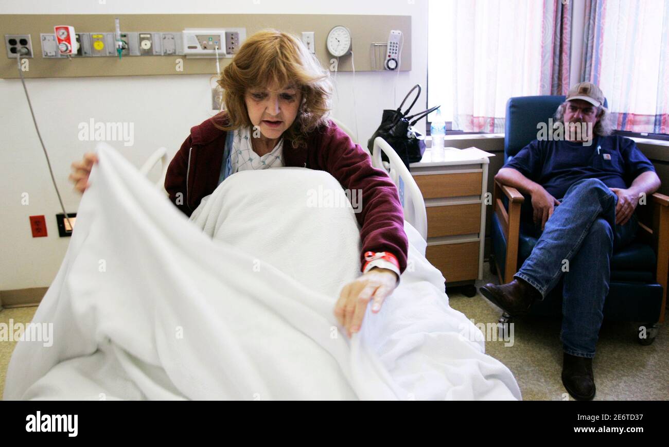 Hannah Hann, who underwent transplant surgery to receive a kidney from her husband Jim (R) in February, adjusts her bedcovers while waiting for tests at Georgetown University Hospital in Washington May 18, 2009. When Jim Hann learned he would be laid off, he scheduled surgery to donate a kidney to his wife. Hann was one of those trying to compensate for losing health insurance in a country where unemployment often means going without coverage.  Picture taken May 18, 2009.  To match feature USA-HEALTHCARE/UNINSURED  REUTERS/Hyungwon Kang   (UNITED STATES HEALTH POLITICS) Stock Photo
