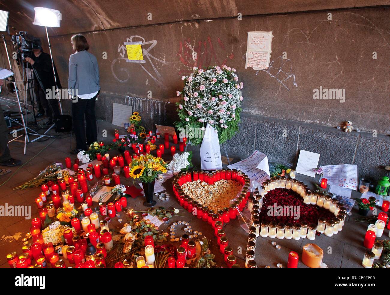 A TV journalist of Germany's public broadcaster Zweites Deutsches Fernsehen (ZDF) waits for the live-broadcast in front of flowers and candles in a tunnel in Duisburg July 27, 2010, near the site where 'Love Parade' goers died in the western German city of Duisburg on Saturday. Police warnings about the dangers of holding the Love Parade in the German city of Duisburg were not heeded, the police union chief said on Monday, as the death toll from a stampede at the event rose to 20. The revellers died when panic broke out at the techno music festival on Saturday in the western city near the Dutc Stock Photo