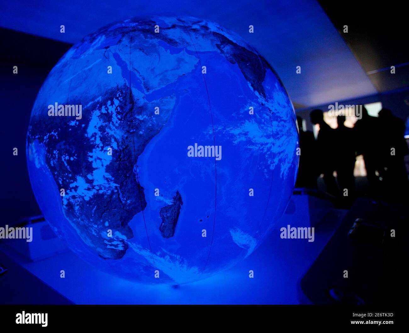 Visitors walk past an illuminated globe displayed on an information stand about Hybrid Synergy drive at the Frankfurt International Auto Show IAA in Frankfurt September 12, 2007. After two days for the media and analysts the Frankfurt motorshow will be open to the public from September 13 to 23. Green technology and lower fuel consumption will be a big theme at the largest and most prestigious auto show in the world this year.  REUTERS/Christian Charisius (GERMANY) Stock Photo