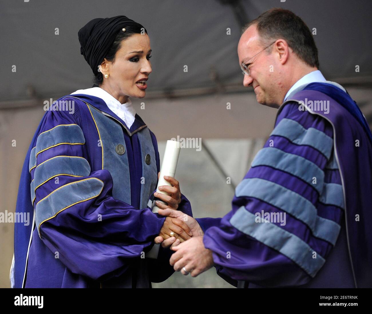 Qatar's first lady Sheikha Mozah bint Nasser Al Missned (L) holds her honorary degree as she shakes hands with Georgetown University President John DeGioia at Georgetown University's commencement exercises in Washington, May 17, 2008. Her Highness addressed the event with the theme 'The Practice of Knowledge', challenging the graduates to use their skills and insights to bring about positive change in the world.   REUTERS/Mike Theiler (UNITED STATES) Stock Photo