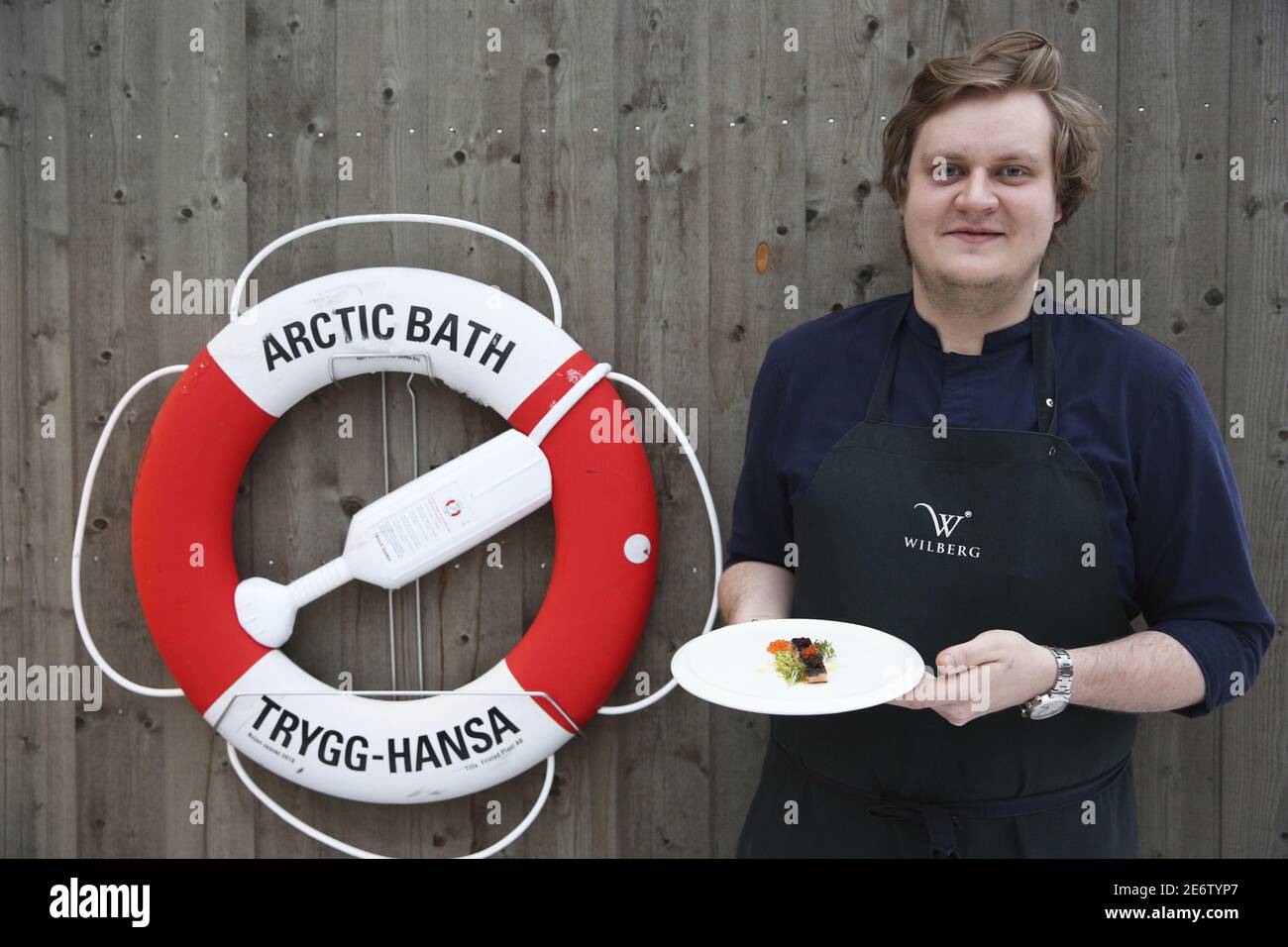 Sweden, Lapland, Norrbotten County, Harads, David Staf, the chef of the Arctic bath hotel presenting a dish of salmon in front of a buoy placed on a wooden wall Stock Photo