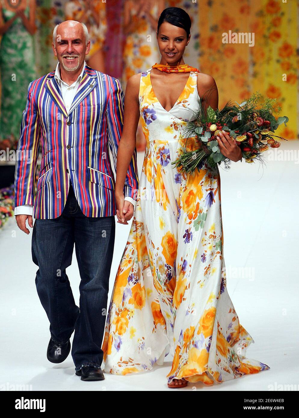 Italian designer Alviero Martini (L) walks the stage with a model at the  end of his