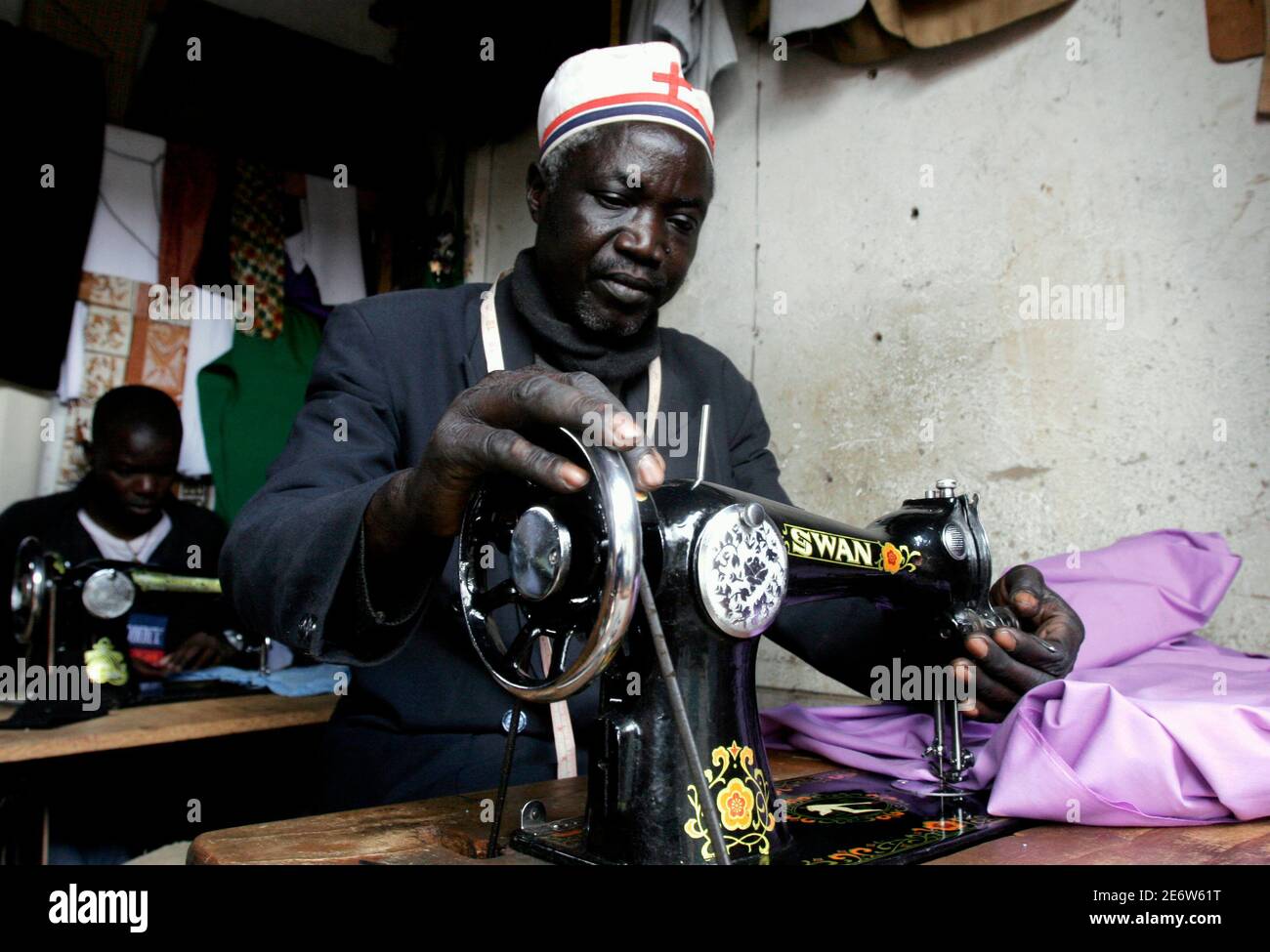 Chrispin Amolo repairs an outfit in Kibera slums, home to more than 800,000 people in Kenya's capital Nairobi, December 6, 2006. The world's slum population is set to grow by 27 million per year between 2000-2020, according to the U.N. Human Settlements Programme U.N.-HABITAT. In sub-Saharan Africa, about 72 percent of the urban population already live in slums, and the annual growth rate is the highest in the world at 4.53 percent. Photo taken December 6, 2006.  To match feature CITIES/KENYA-SLUM  REUTERS/Thomas Mukoya (KENYA) Stock Photo