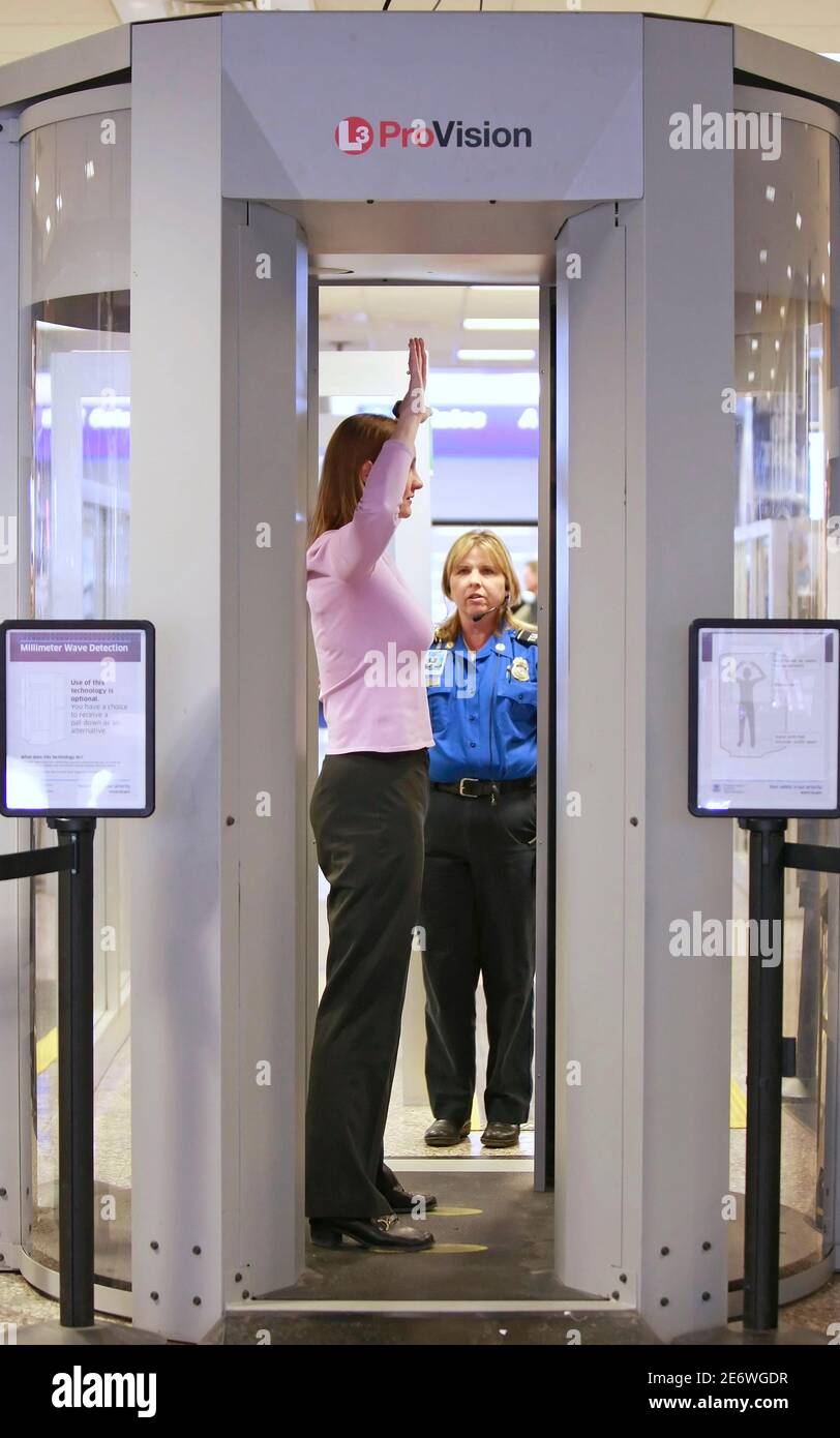 A Transportation Security Administration (TSA) officer scans a woman  through with a whole body scan machine, or millimeter wave machine at a  security check point at the Salt Lake International Airport in