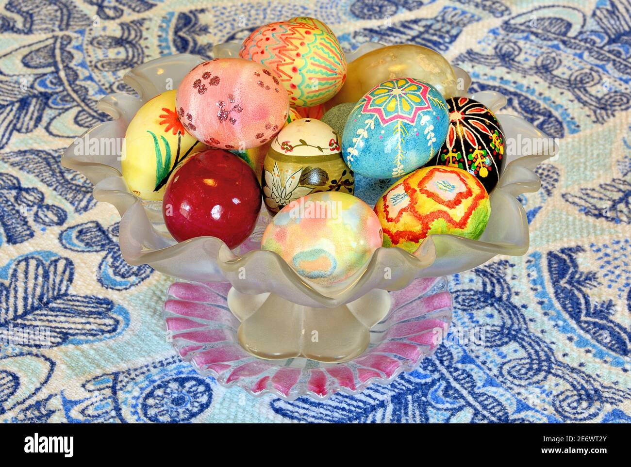 Seasonal Easter theme. Artistic arrangement of colorful and ornate hand-painted easter eggs in vintage glass bowl. Stock Photo