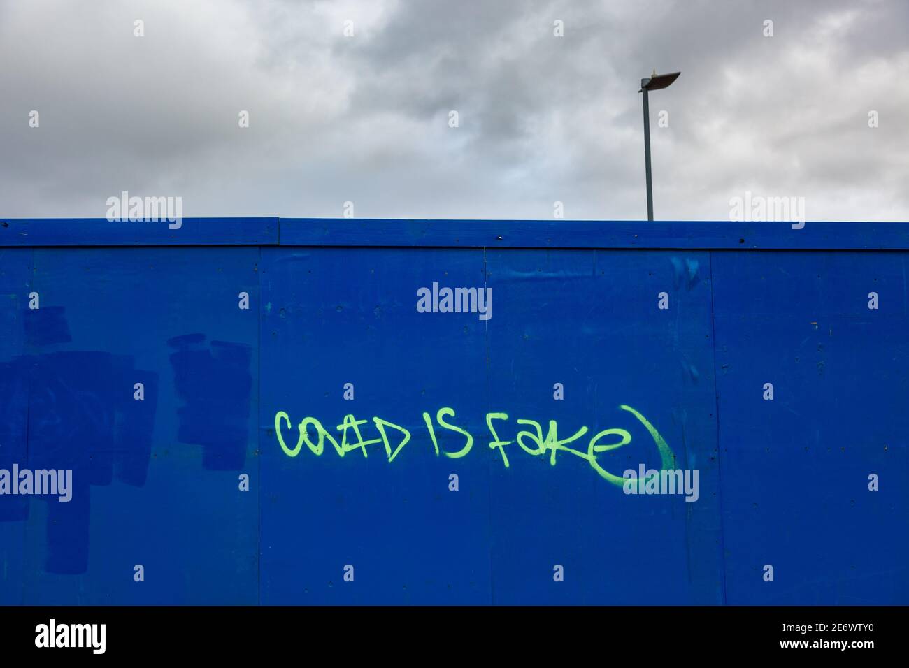Covid is fake grafitti on a hoarding, 2021 Stock Photo